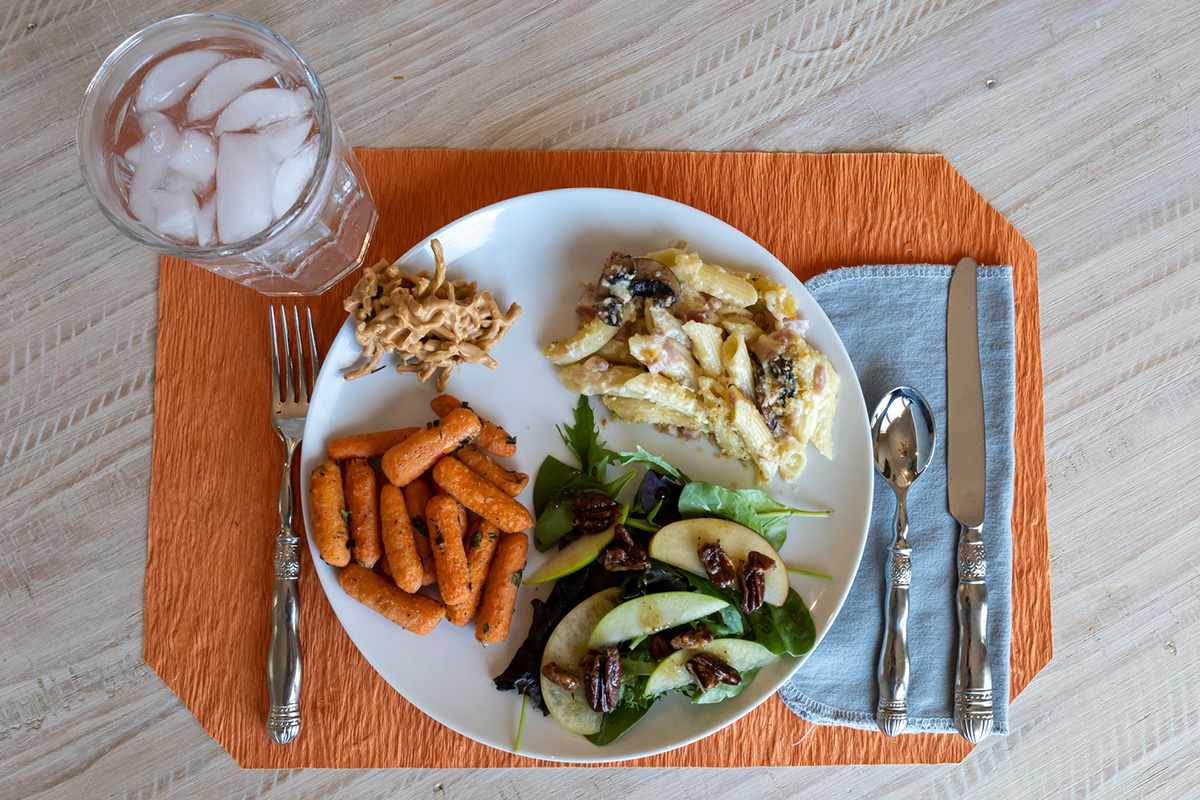 Pasta, carrots, a spinach salad, and cookies on a plate display Pasta, carrots, a spinach salad, and cookies on a plate display
